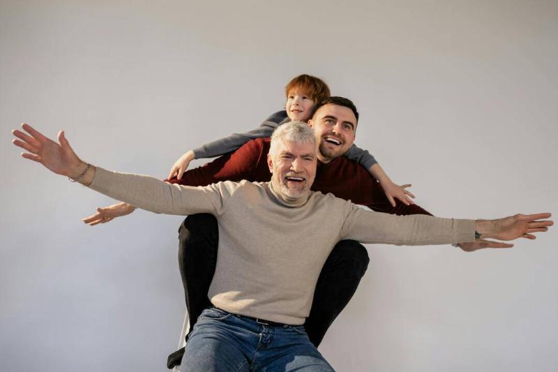 A grandfather, his son, and his grandson all stacked on top of one another in a faux piggyback ride.