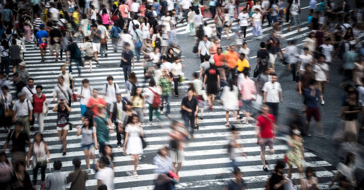 A timelapsed photo of many people crossing a big intersection.