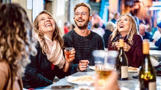 Three friends sat around a table, drinking and laughing.