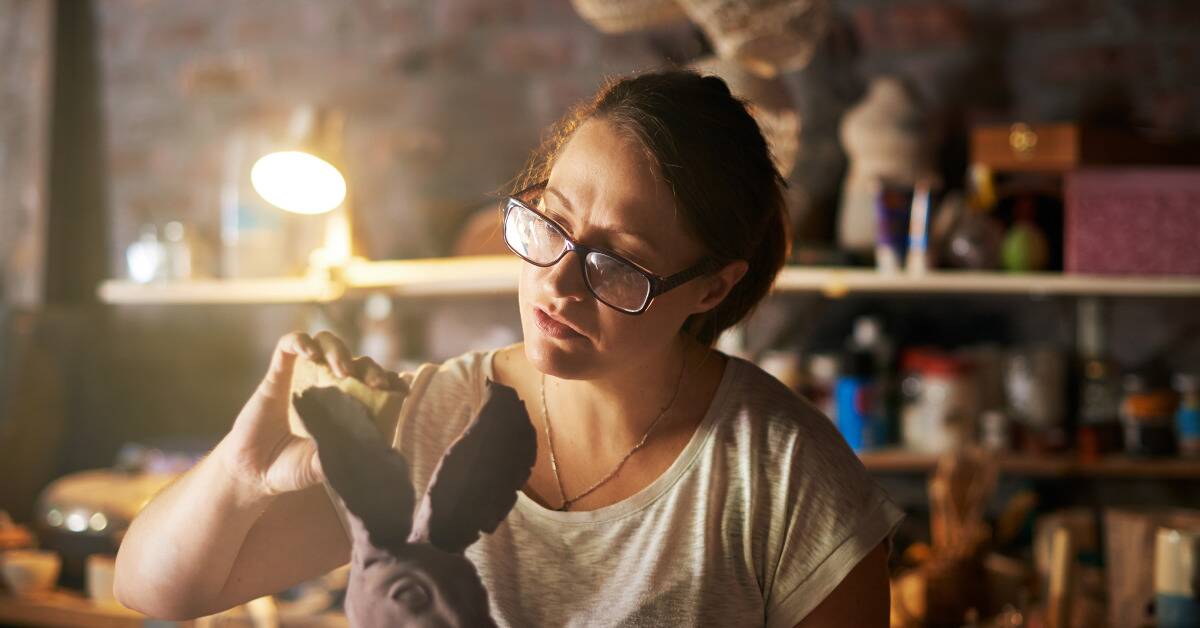 A woman working on a clay sculpture.