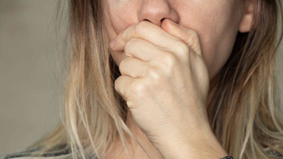 A close shot of a woman covering her mouth with her hand.