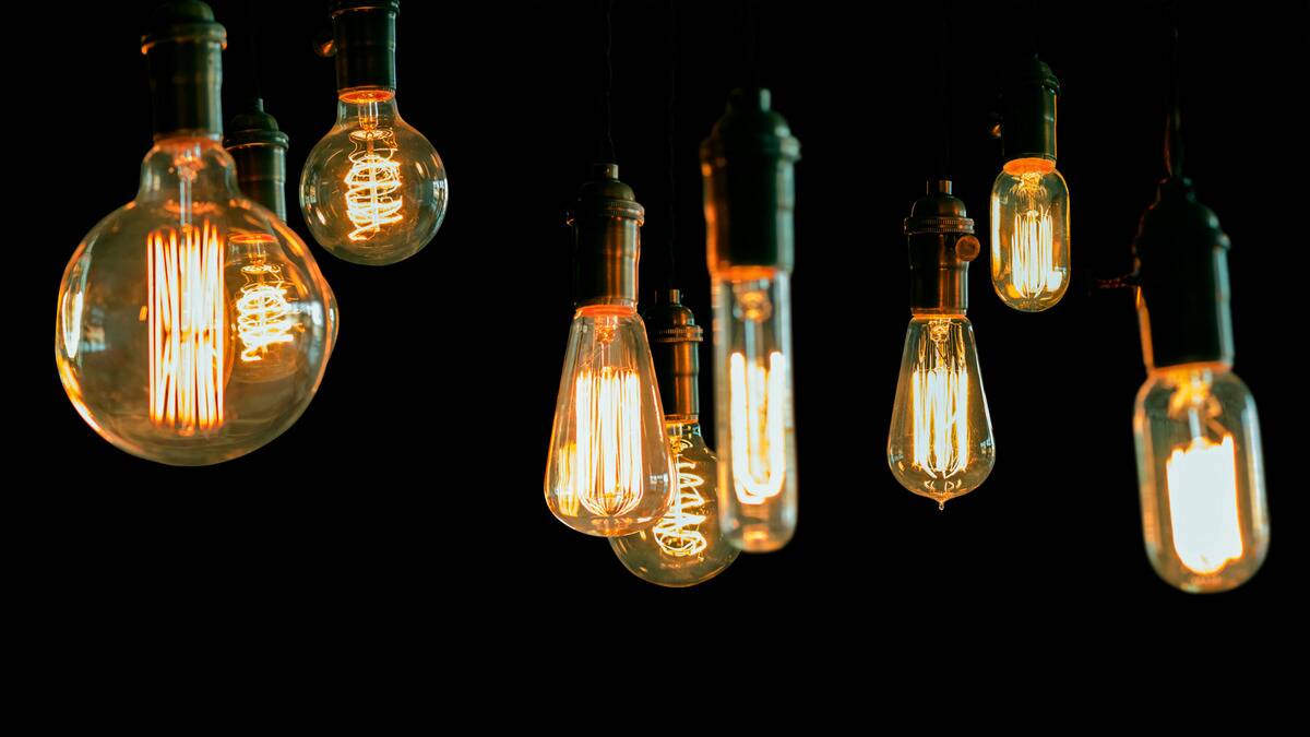 A lineup of light bulbs in all different shapes hanging from above.