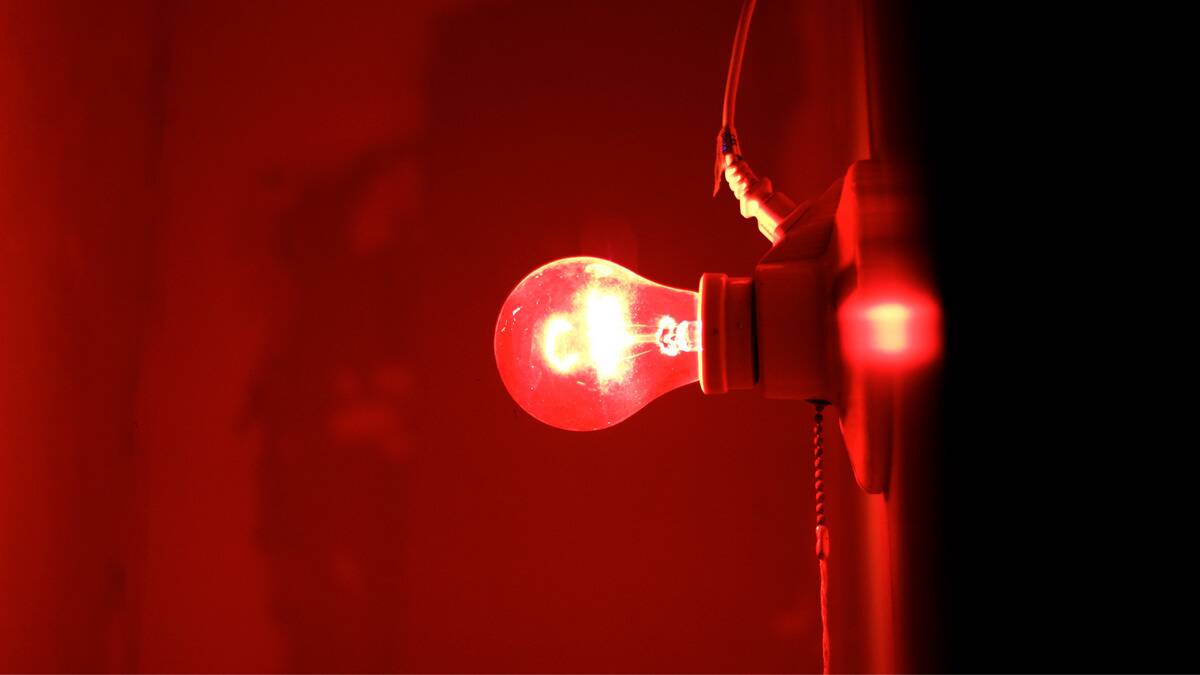 A red light bulb shining brightly on a wall.
