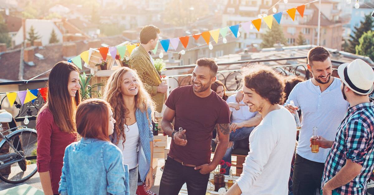 People smiling as they chat during a rooftop party.