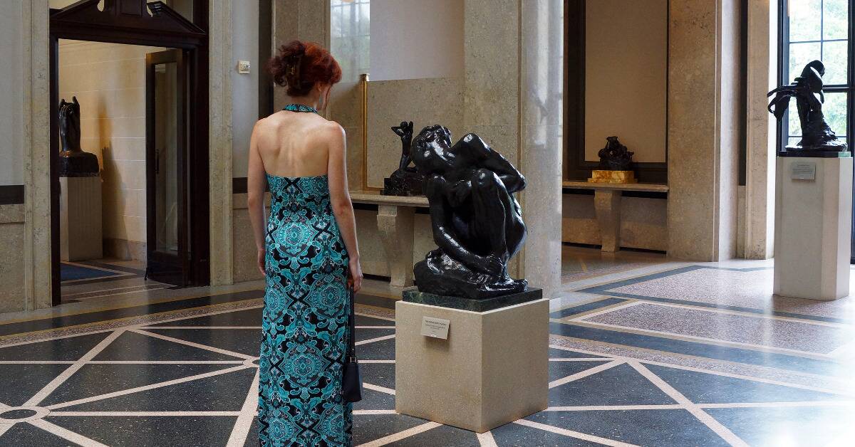 A woman looking at a sculpture in a museum.