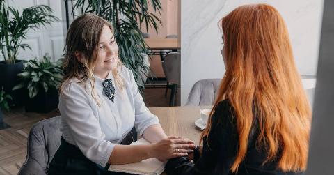 Two women talking, holing hands across the table and listening to one another.