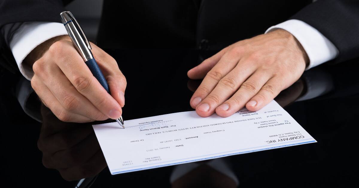 A pair of hands writing a cheque.
