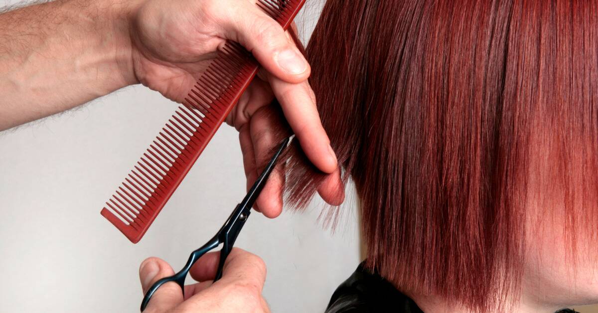A close shot of someone with dyed red hair in a bob cut getting a trim.