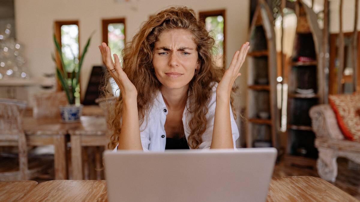 A woman looking at her laptop with a confused, frustrated expression.