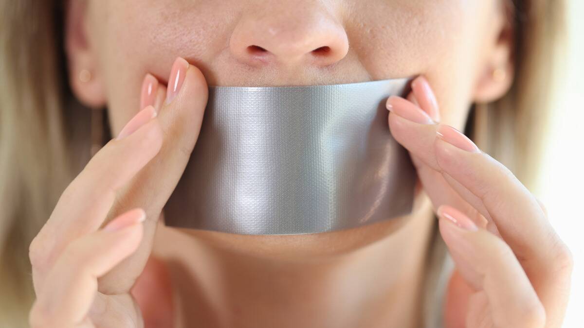 A woman putting duct tape over her mouth.