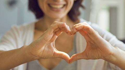 A close shot of a woman holding her hands out in a heart shape.