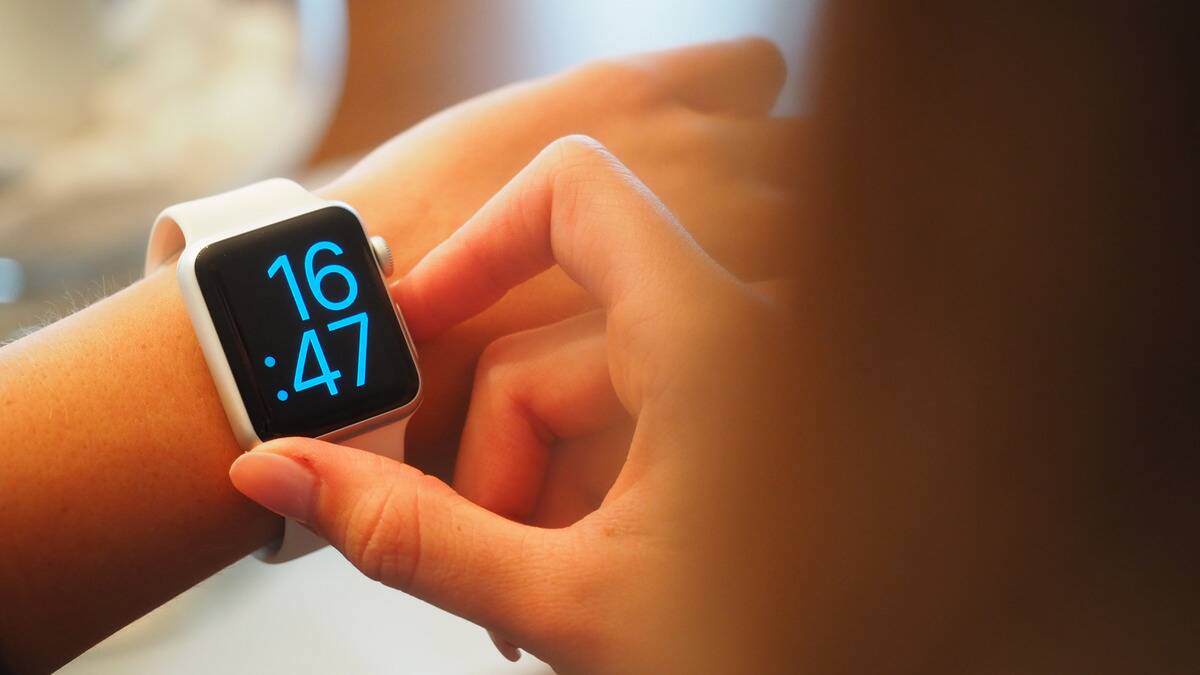 A woman pressing a button on her smart watch that's currently displaying the time.