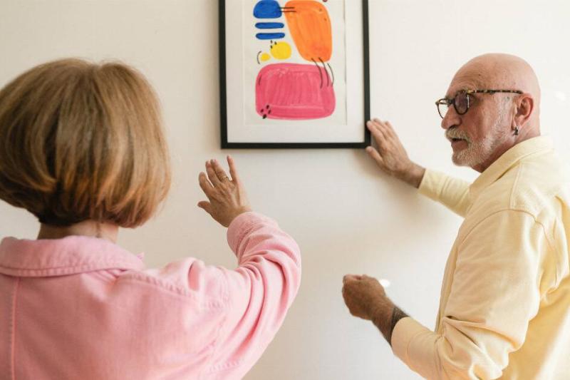 Two people discussing how and where to hang up a piece of artwork.