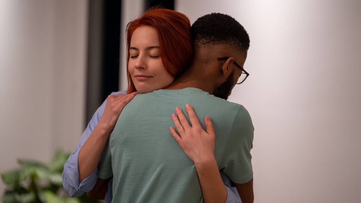 A couple hugging, the woman's face seeming happy and at pease.