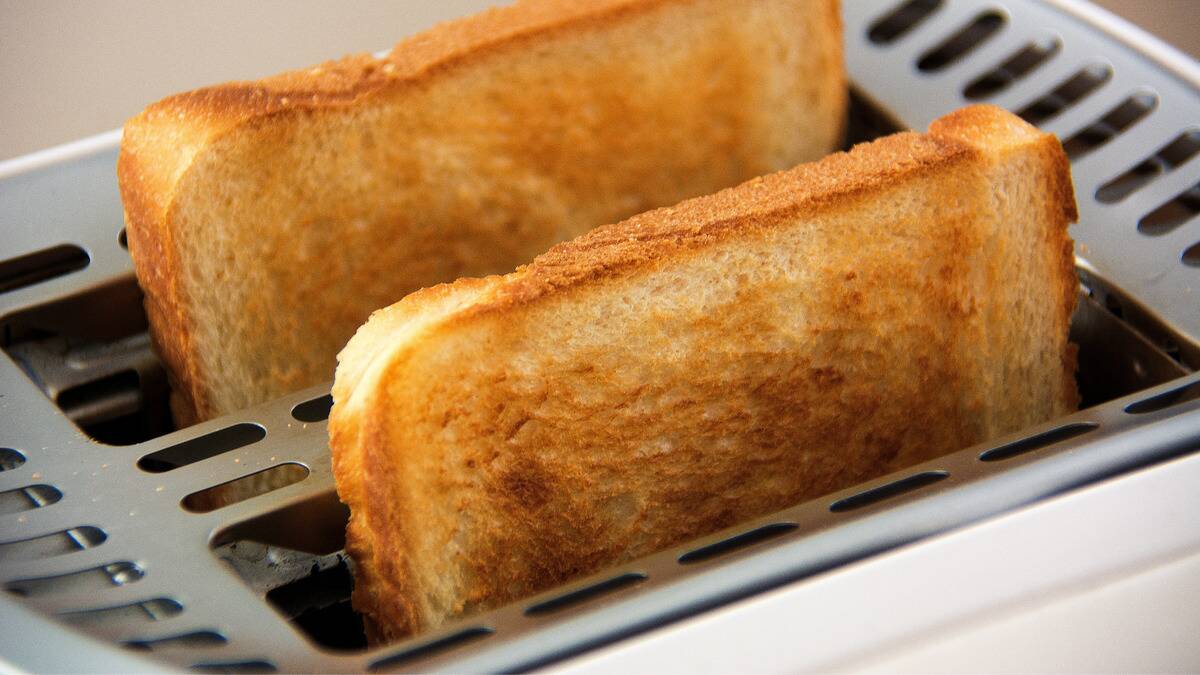 Two pieces of perfectly toasted bred popping out of a toaster.