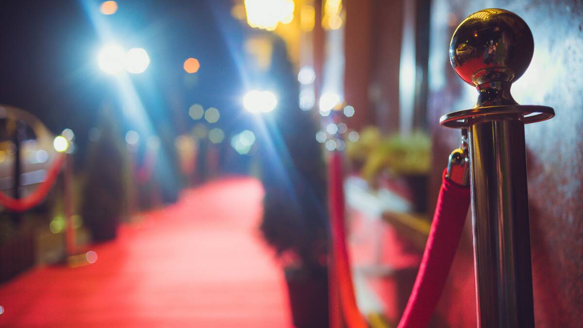 A blurry photo of a red carpet with camera flashes surrounding it.