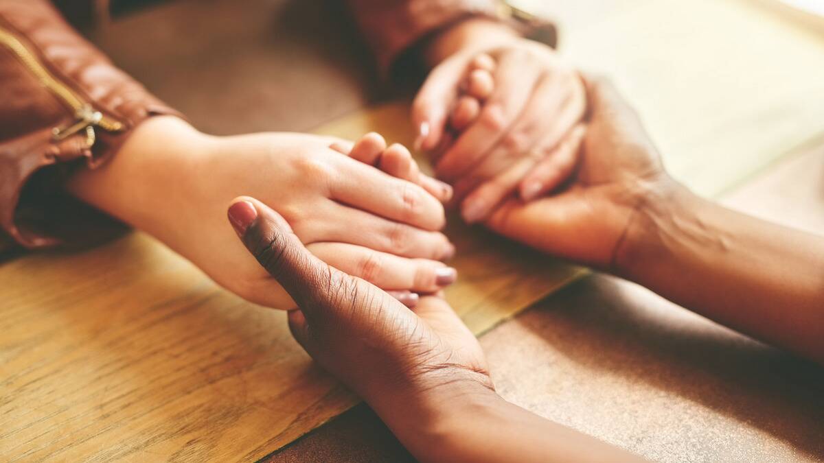 A close shot of someone holding another person's hand in their own in a comforting motion.