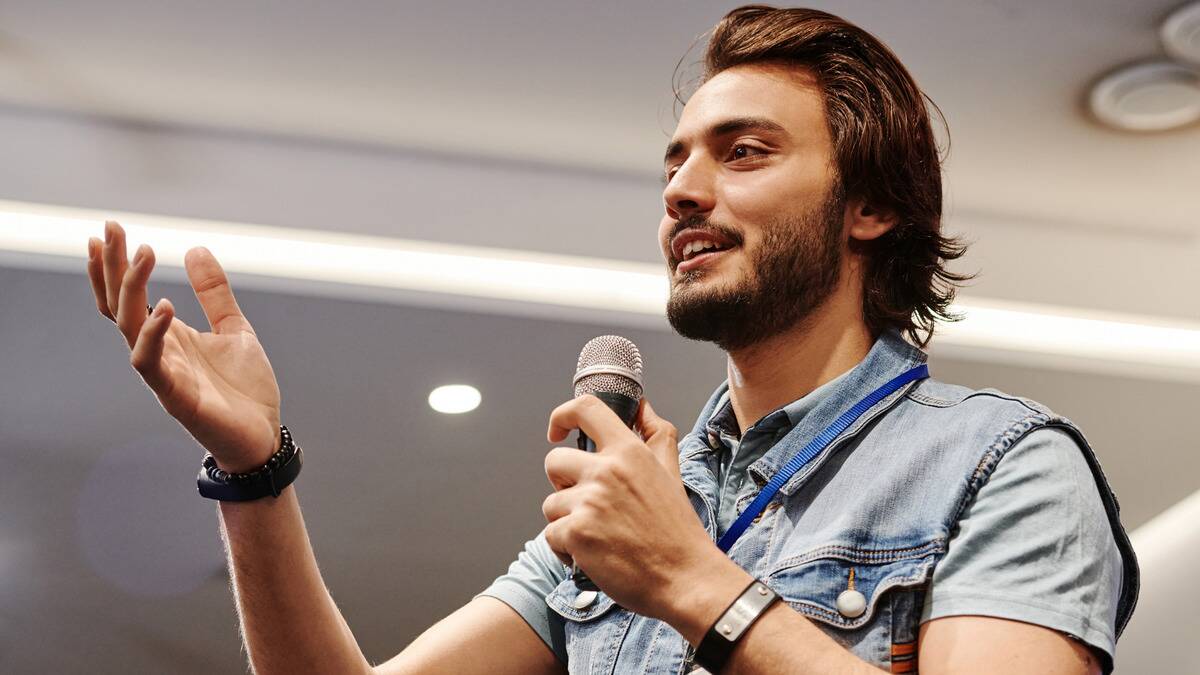 A man speaking confidently into a microphone at a conference.