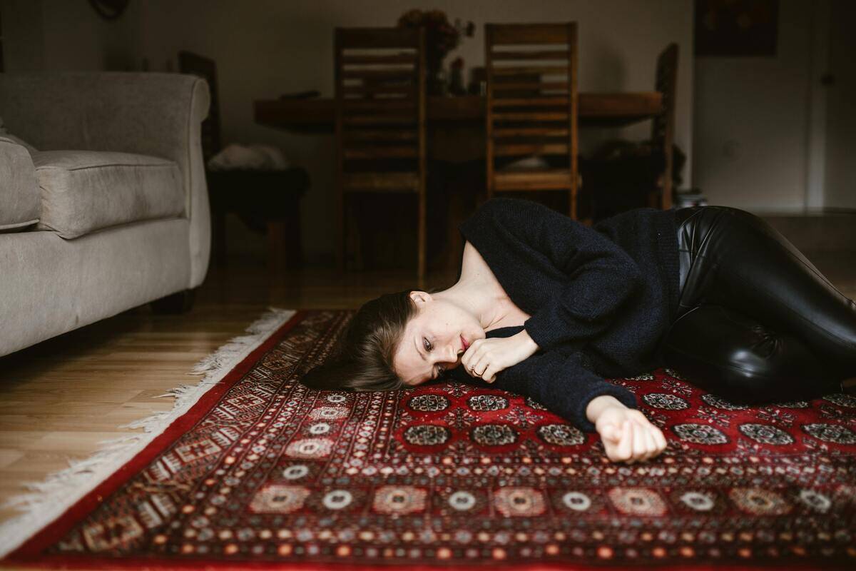 A woman laying on a rug on the floor, as if she's too sad to move.