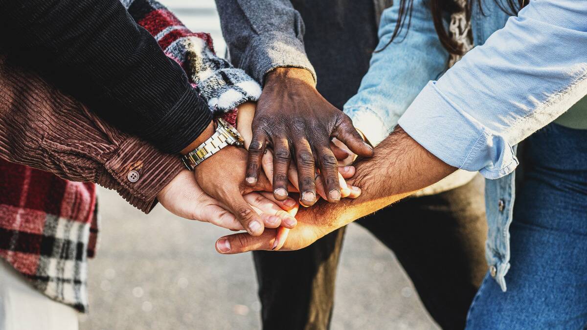 A close shot of a group of peoples' hands placed together in a group cheer.