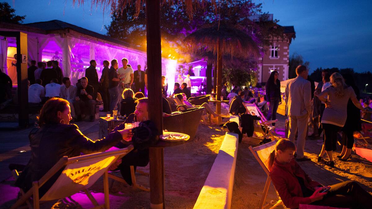 A nighttime beach party lit in purple and yellow.