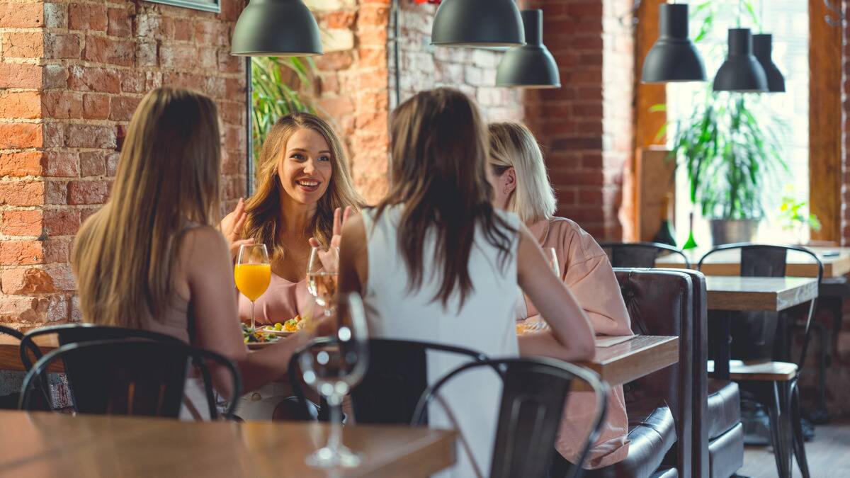 A group of women talking around a restaurant table.