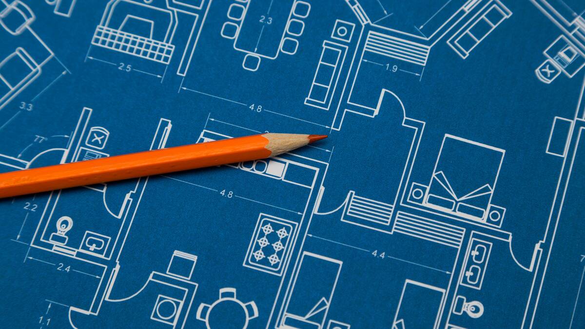 An orange pencil on top of some blueprints.