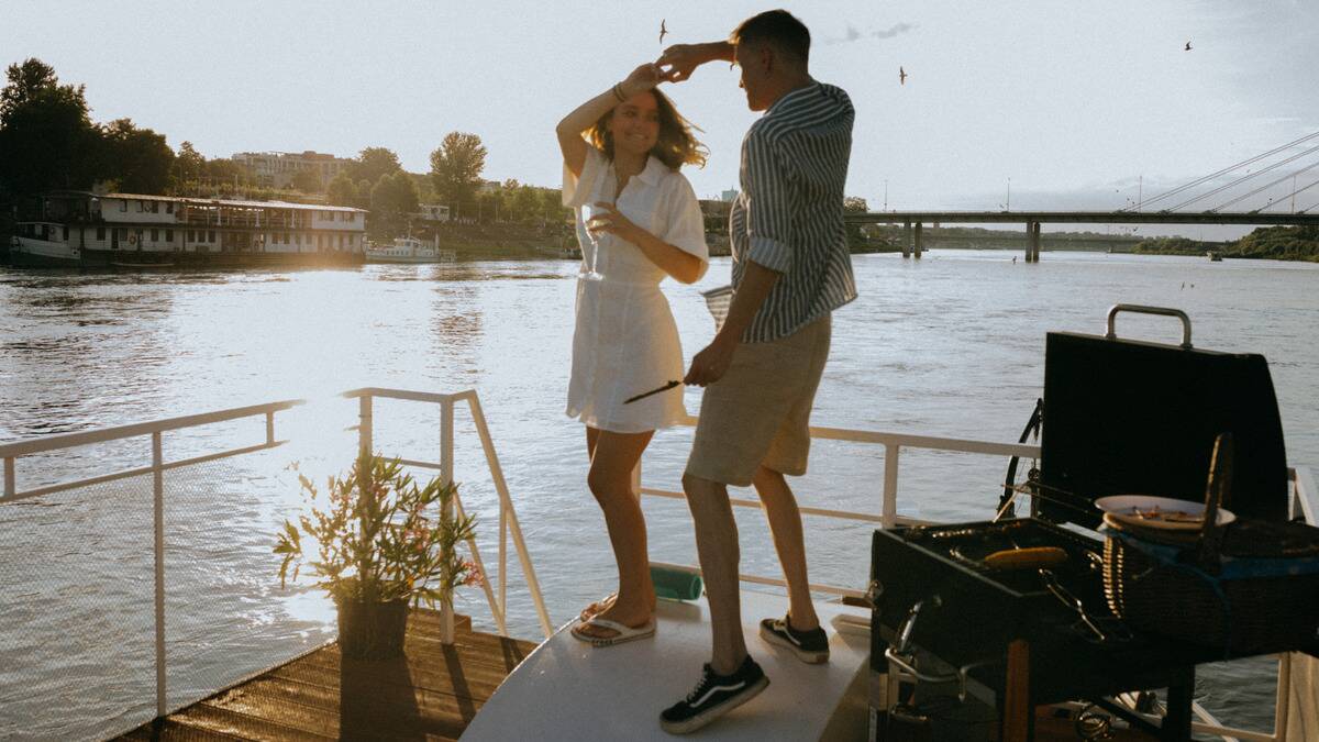 A couple dancing on a waterside dock in the summertime.