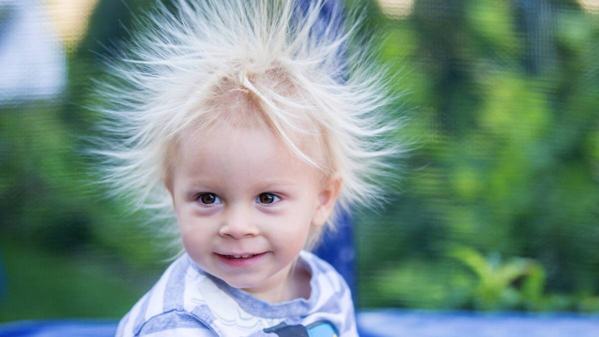 A young boy whose hair is sticking straight up thanks to static.