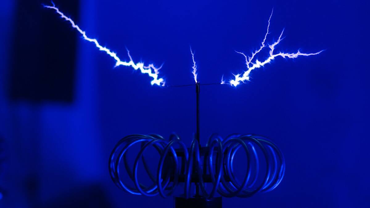 An electrical coil in a blue-lit room, a few bright white bolts shooting off it.
