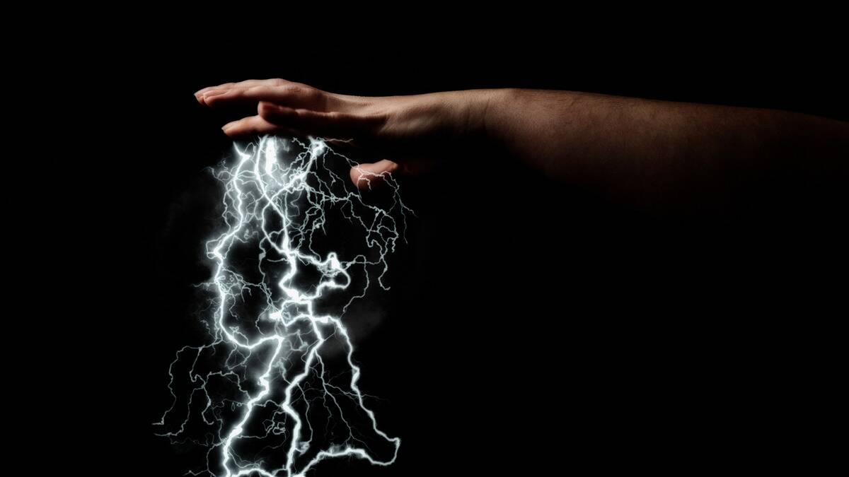 A dark, shadowed shot of a hand facing palm-down with a rain of white lightning bolts coming from it.