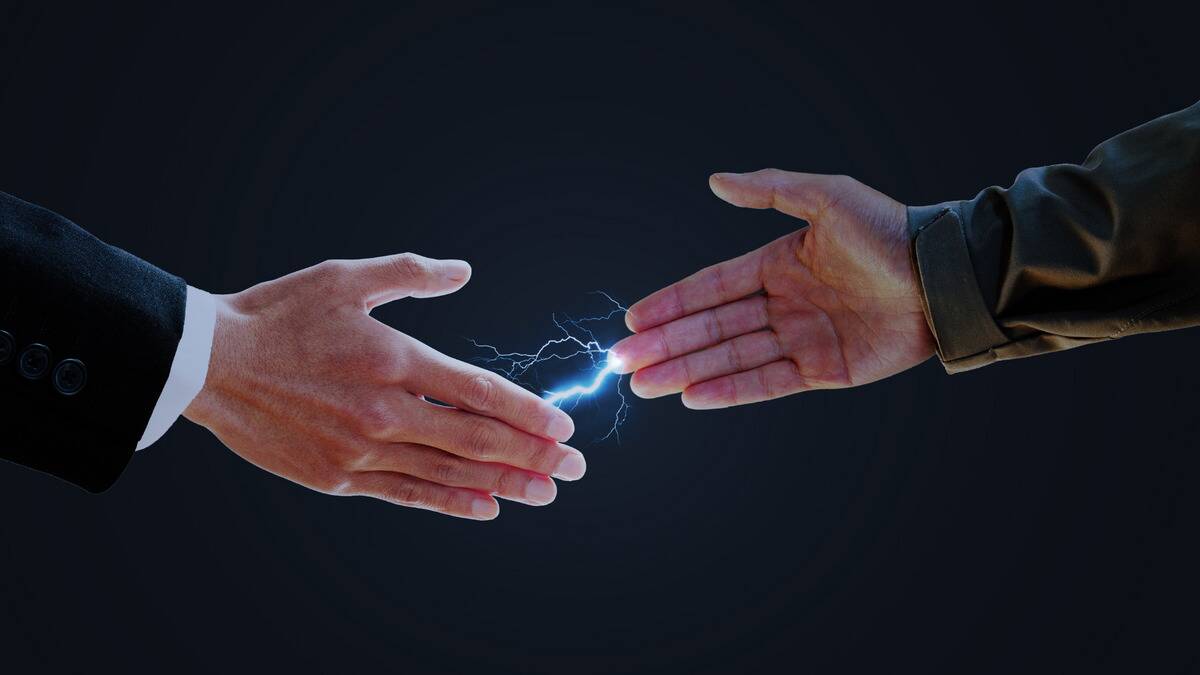 Two people reaching to shake hands, a static bolt edited between their fingers.