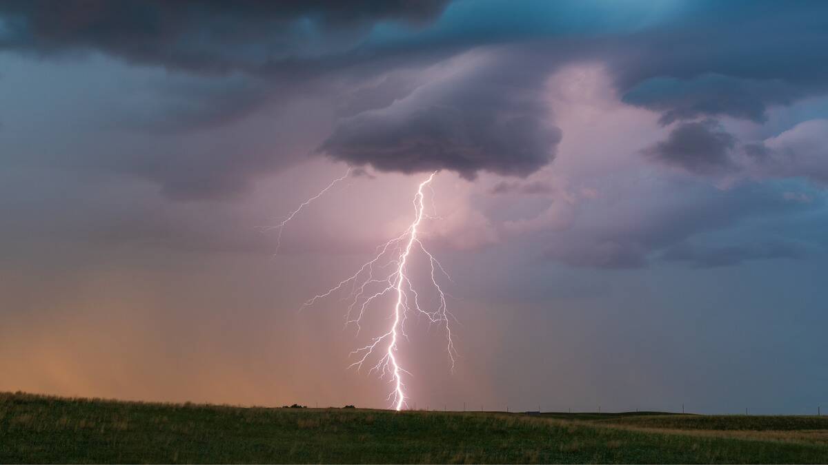 A single, striking lightning bold descending from a cloud to a point in a flat plain area.