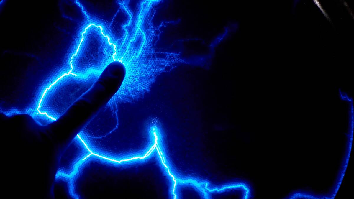 A close shot of a finger pressing against a static lightning light, the bolts drawn to the touch.