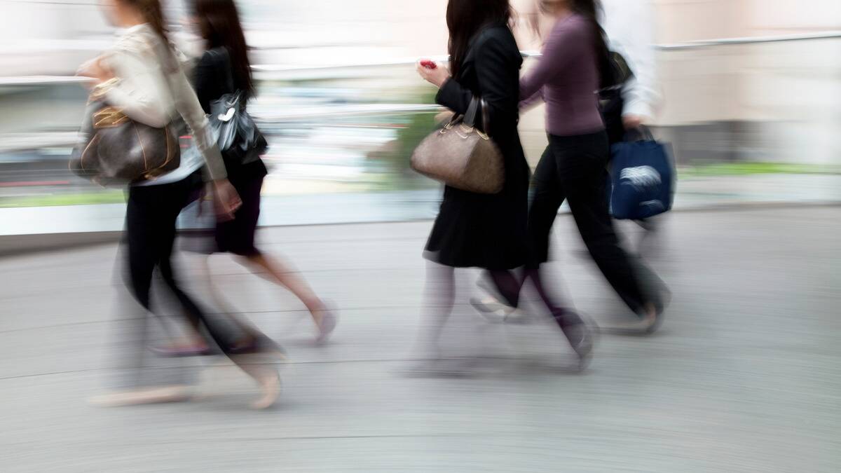 A purposefully blurry image showing a group of business woman walking quickly, as if late for something.