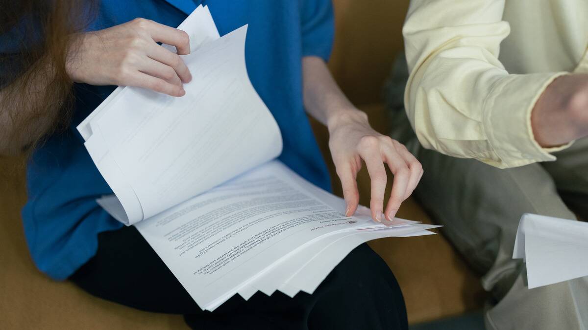 A woman sorting through a stack of paperwork in her lap.