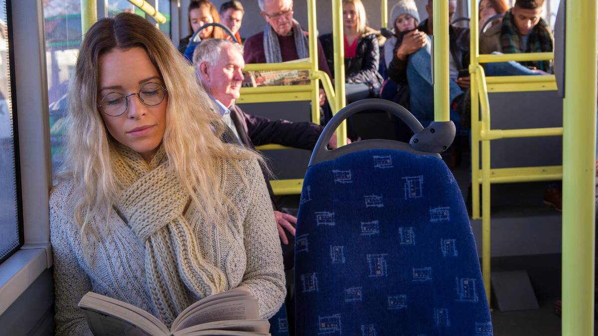 A woman sitting on the bus reading a book.