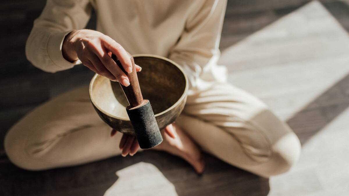 An above angle shot of someone using a singing bowl as they meditate.