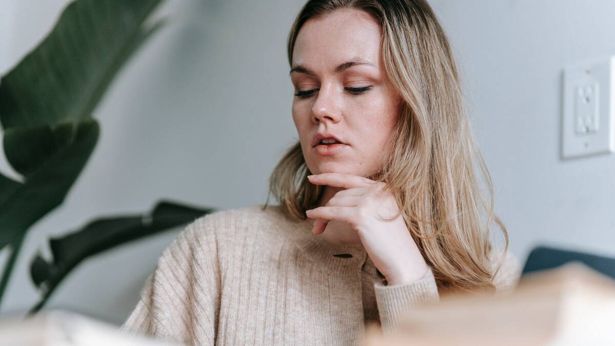 A close shot of a woman with her hand on her chin, seeming to be thinking about something.