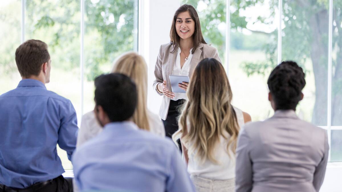 A woman standing in front of a group, giving a work presentation.