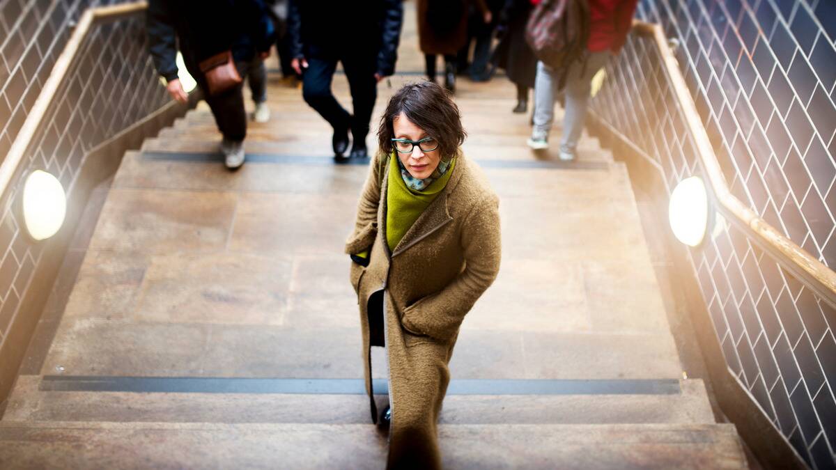 A woman walking up some stairs, standing ahead of a crowd just behind her.