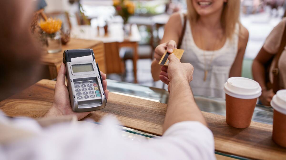 A woman handing a barista her credit card to pay for her drink.