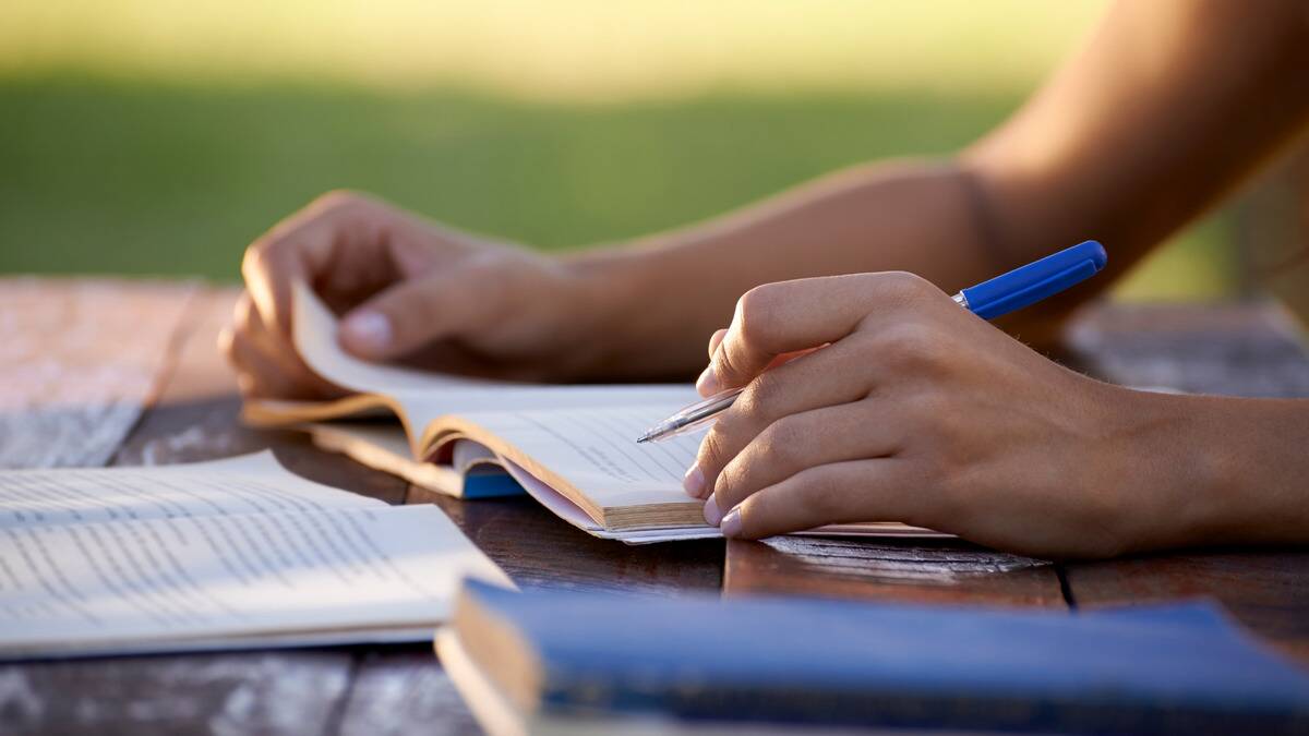 A close shot of someone studying at a table outdoors.