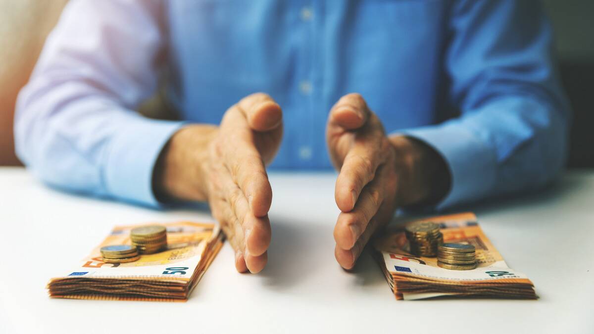 A close shot of some hands on a table separating two stacks of bills and coins.