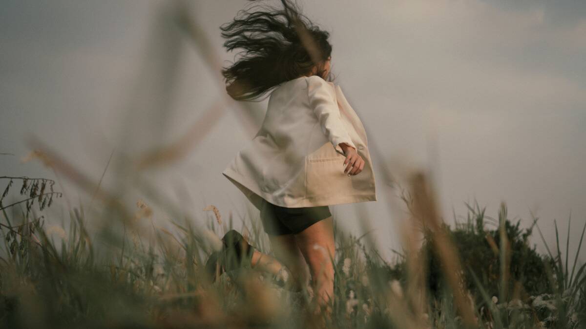 A woman running through a grassy field.