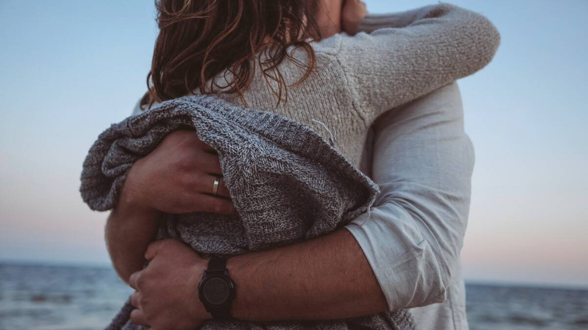 A close shot of a couple hugging on the beach.