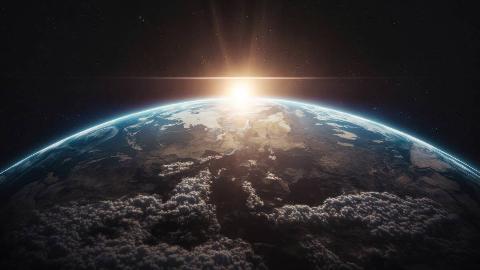A render of the light of the rising sun cresting Earth's surface in space.