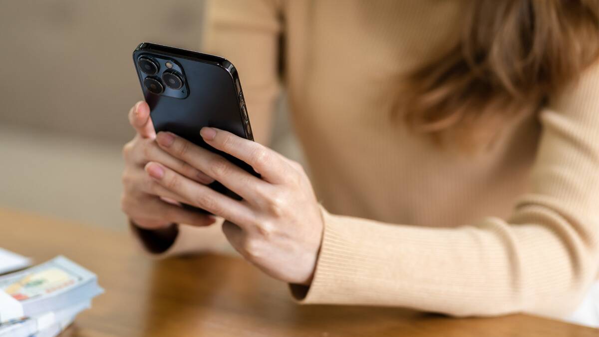 A close shot of a woman holding her smartphone, typing something on it.