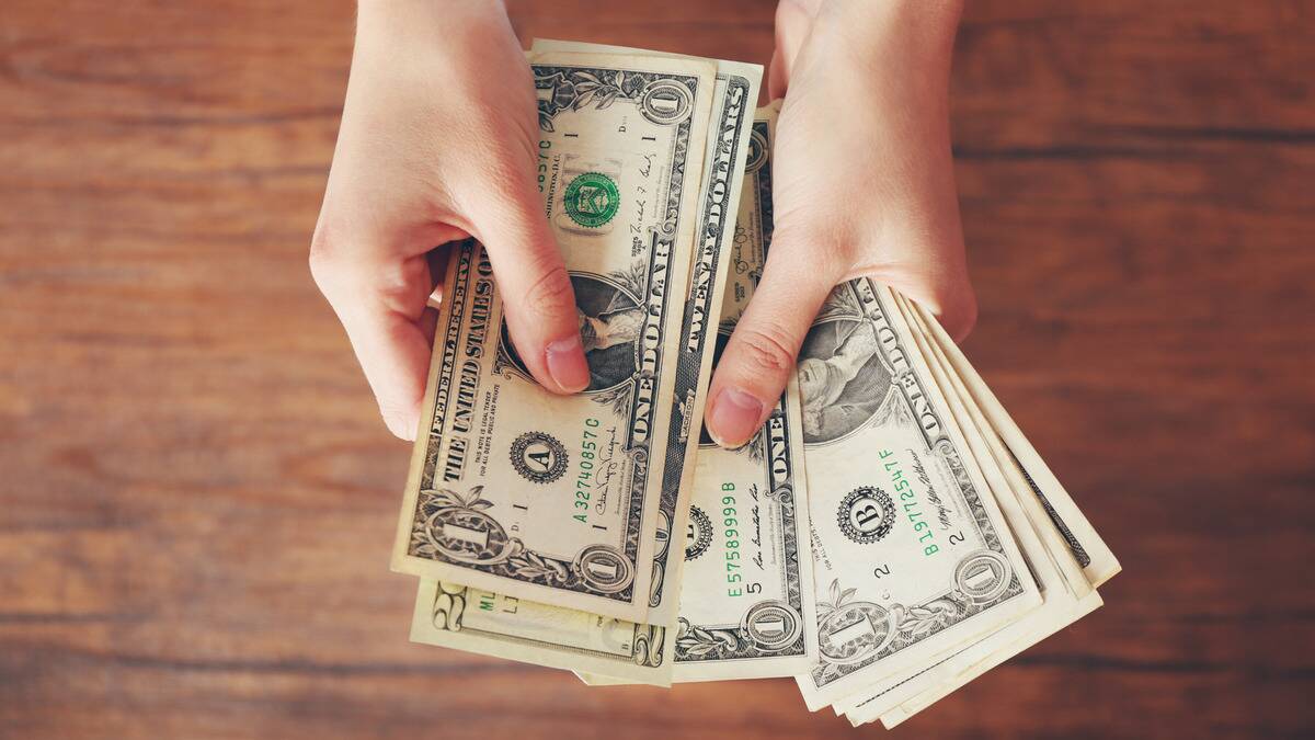 A close shot of someone counting a stack of $1 bills. 