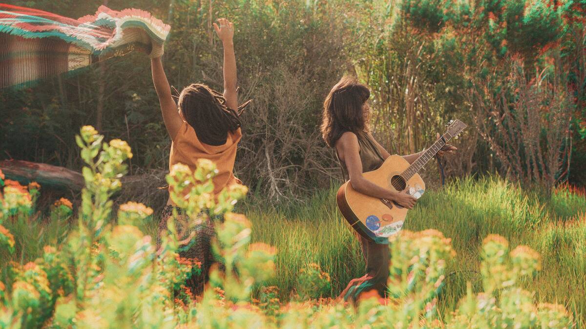 Two friends dancing outside in a photo with a heavy lighting effect, making it feel dreamy.